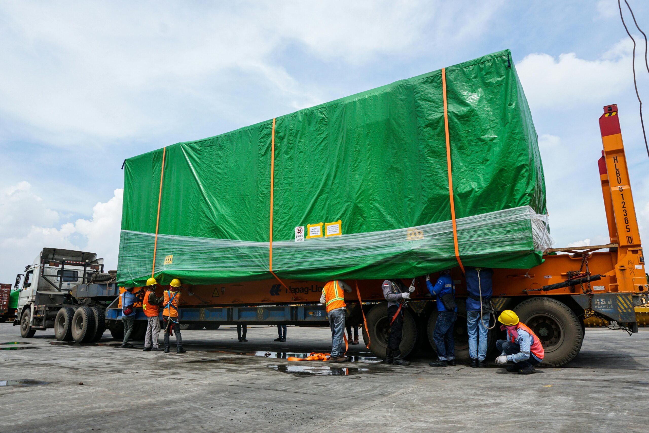 Workers securing an oversized load on a flatbed trailer for heavy equipment transport