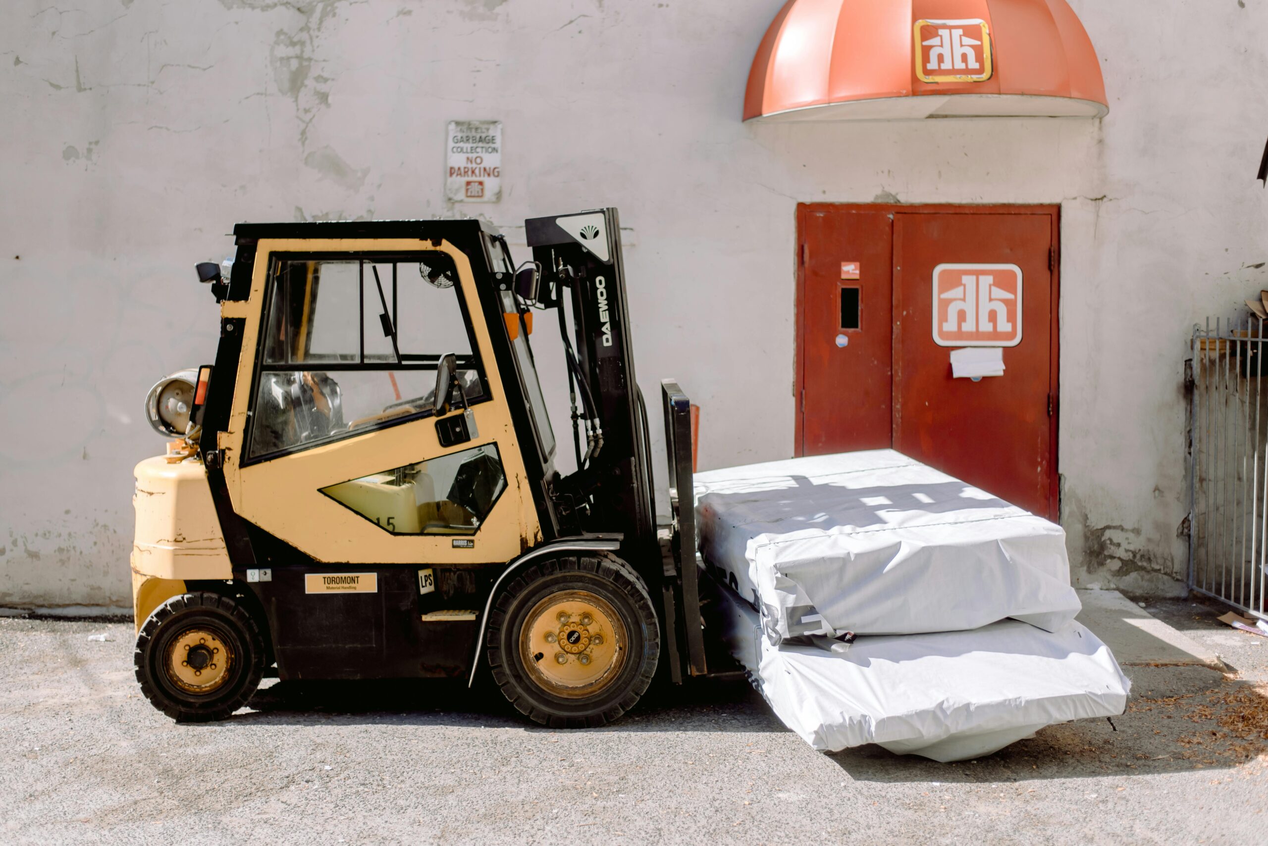 Forklift carrying shrink-wrapped pallets outside a commercial loading dock