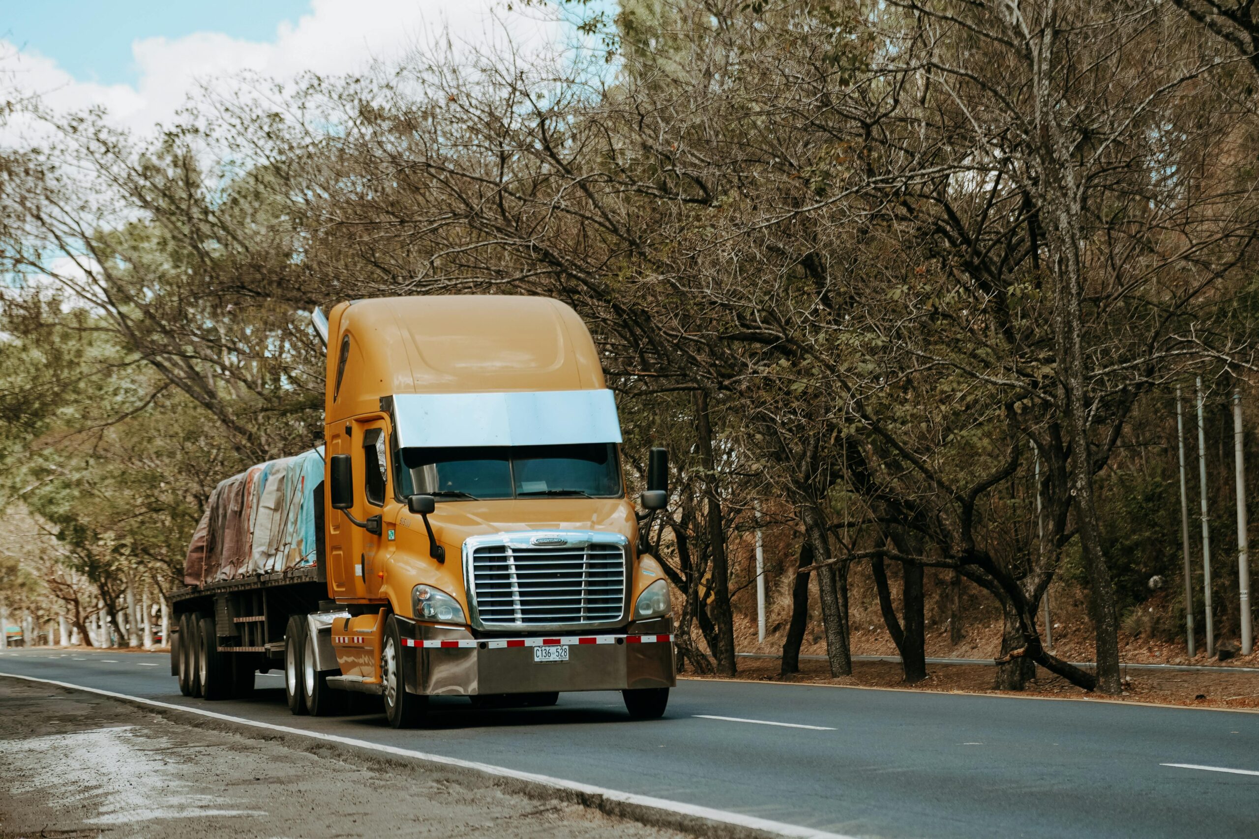 Flatbed truck hauling tarped freight on a highway