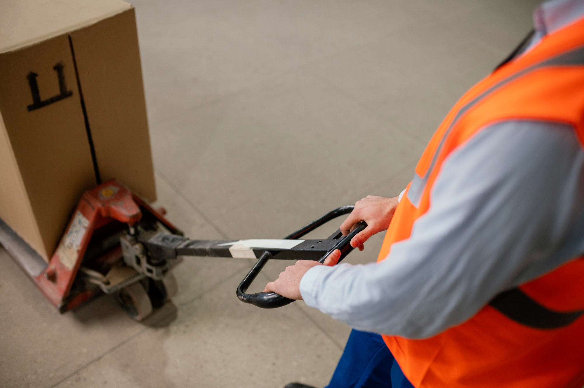 freight worker moving pallet with hand jack